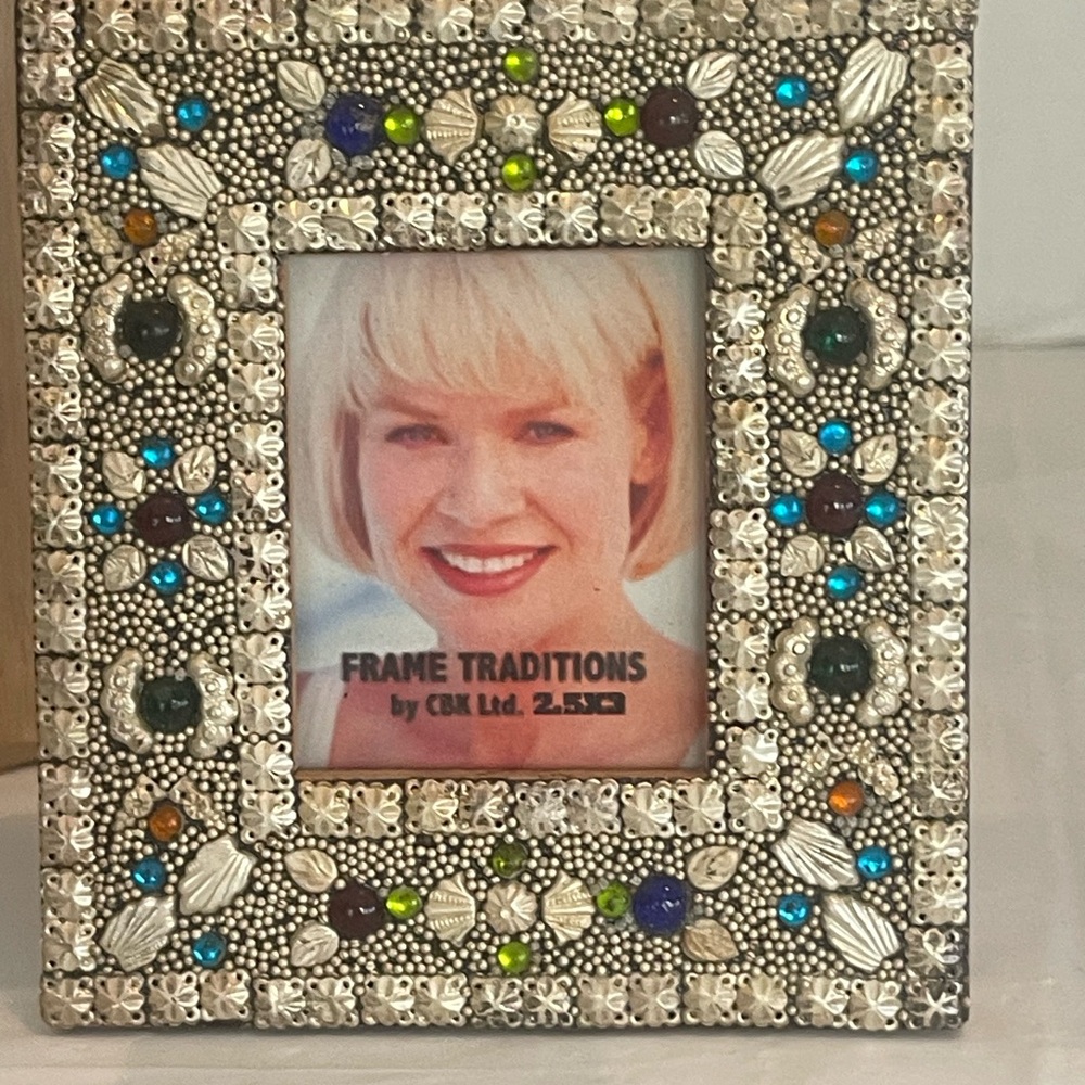 A picture frame features intricate silver-toned beadwork & colored glass accents